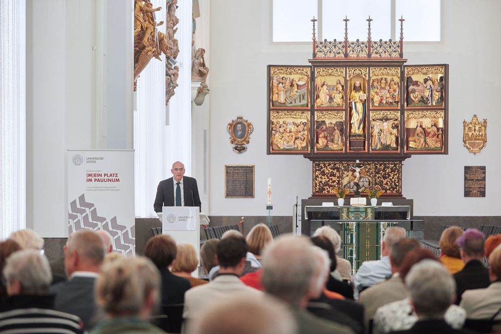 zur Vergrößerungsansicht des Bildes: Professor Eilers steht vor dem Publikum am Rednerpult, im Hintergrund sind der Paulineraltar und ein Teil der Epitaphien im Paulinum zu erkennen