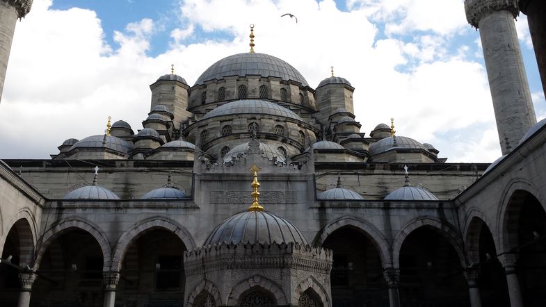 Eine Moschee mit vielen kleinen und größeren runden Kuppeln. Die Moschee besteht aus hellem Stein, welcher an vielen Stellen vom Regen schwarz gefärbt ist. Manche der Kuppeln tragen ein goldenes Zepter.