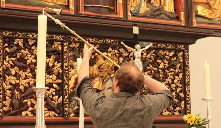 Ein Küster zündet eine Kerze auf dem Paulineraltar an, Foto: Anna Tunger