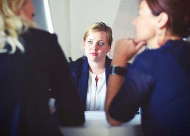 Foto: Tim Gouw / Unsplash Foto: eine junge Frau sitzt in einer Gesprächssituation zwei anderen Frauen gegebüber