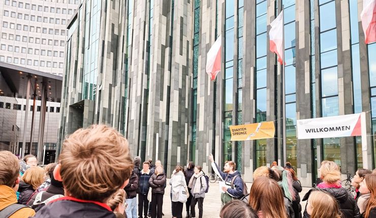 Ein Campusführer steht mit einer Gruppe vor dem Neuen Augusteum