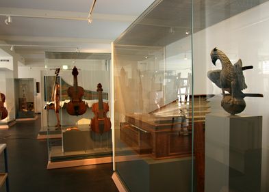 Verschiedene historische Streich- und Tasteninstrumente stehen in dem gezeigten Ausstellungsraum.