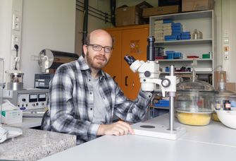 Auf dem Bild ist der neuberufene Professor Dr. Alexander Tsirlin am Mikroskop zu sehen.