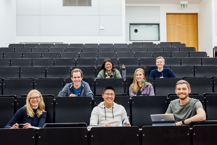 Farbfotografie von sieben Studierenden, den Studienbotschafter:innen, in einem Hörsaal sitzend