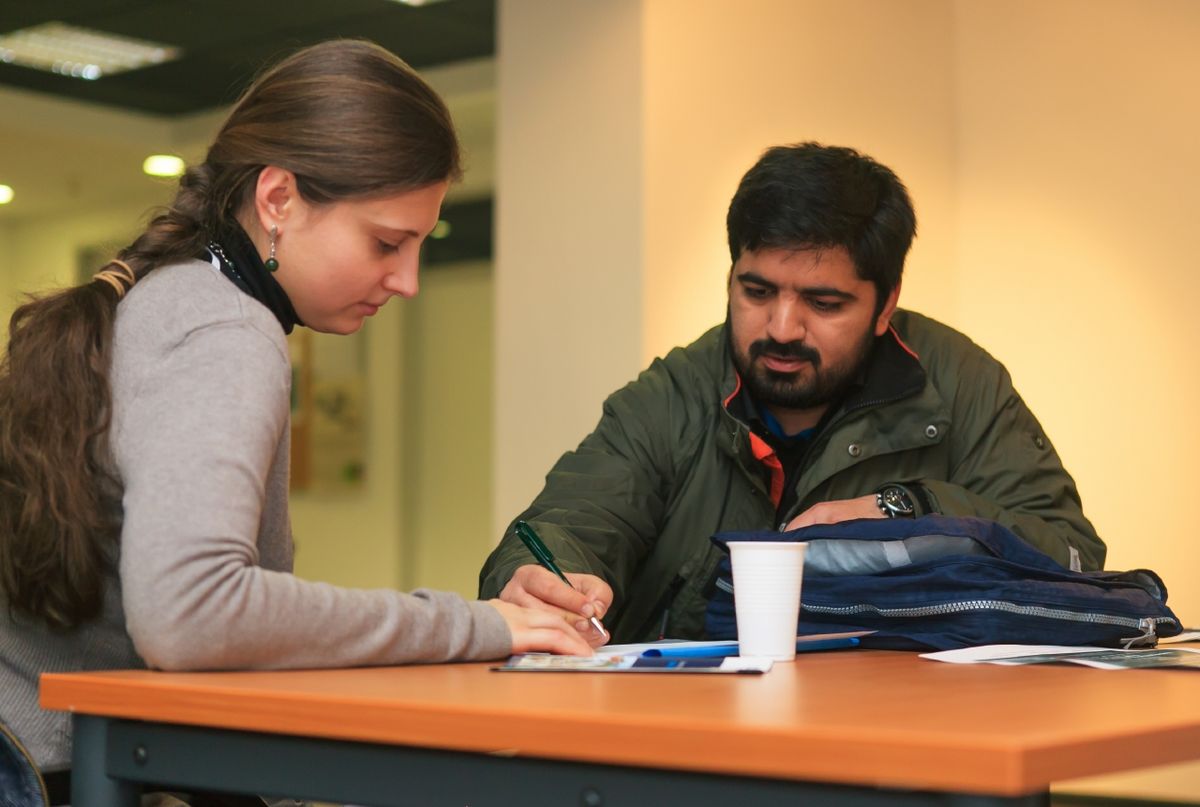 zur Vergrößerungsansicht des Bildes: Foto: Eine Vertreterin der Internationalen Doktorandeninitiative gibt einem ausländischen Interessenten Auskunft während der Informationsmesse zum Tag der Promotion