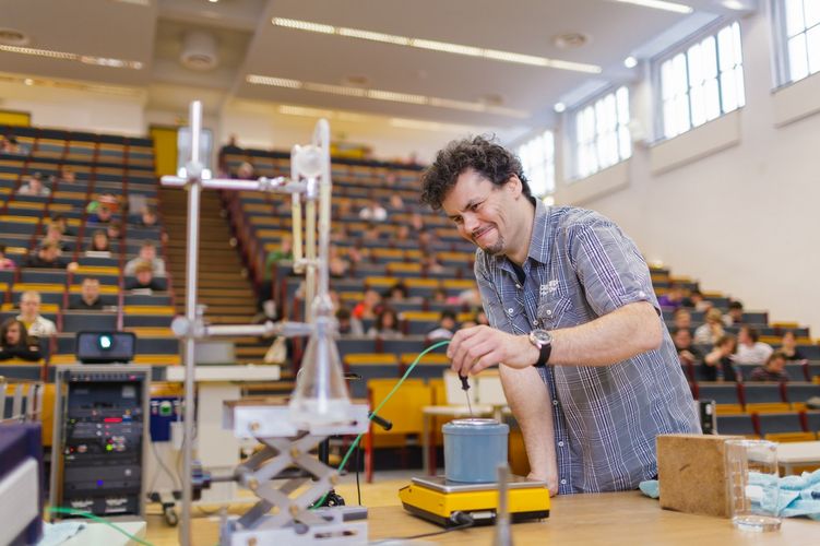 Lecturer stands in front of students in the lecture hall and prepares equipment