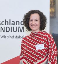 Förderin Pirkko-Maria Herre steht vor dem Deutschlandstipendium Roll up