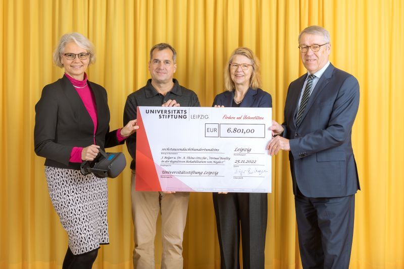 zur Vergrößerungsansicht des Bildes: Farbfoto: Prof. Dr. Birgit Dräger, Dr. Hubert Temmeyer und Prof. Dr. Harald Krautscheid von der Universitätsstiftung überreichen den symbolischen Scheck an die Fördermittelempfängerin Dr. Angelika Thöne-Otto