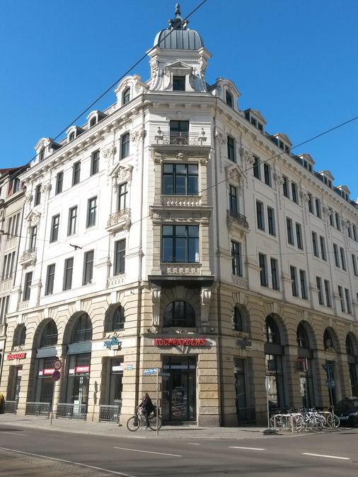 enlarge the image: Farbfoto: Straßenansicht mit Blick auf das Gebäude mit historischer Außenfassade
