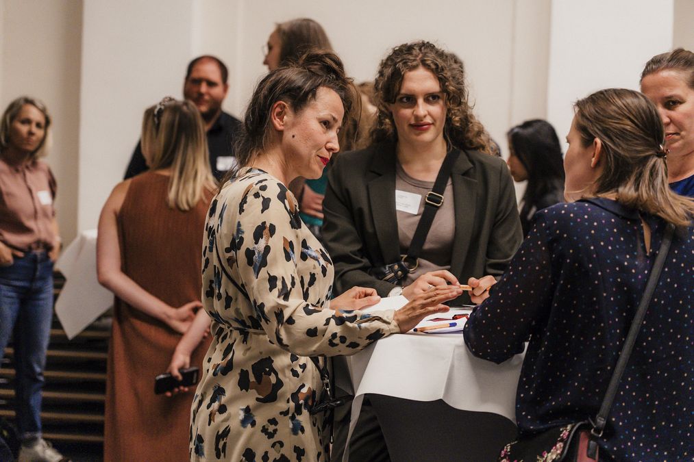 zur Vergrößerungsansicht des Bildes: Blick auf angeregten Austausch zwischen vier Teilnehmenden am Thementisch "Kunst, Kultur & Gestaltung". Im Hintergrund andere Teilnehmende. Foto: Christin Hiebner