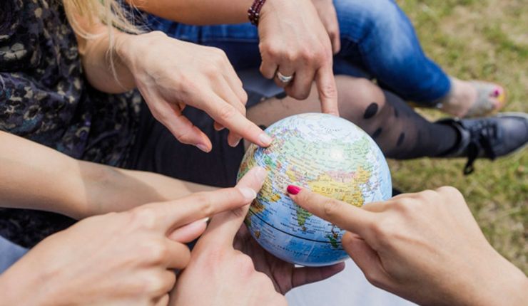 Colour photo: various hands point to a small globe