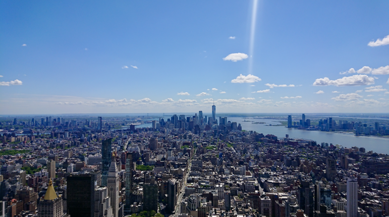 Zu sehen ist die Skyline der Stadt New York City. Das Foto wurde von einem Wolkenkratzer aus aufgenommen. Es sind viele Wolkenkratzer zu sehen.