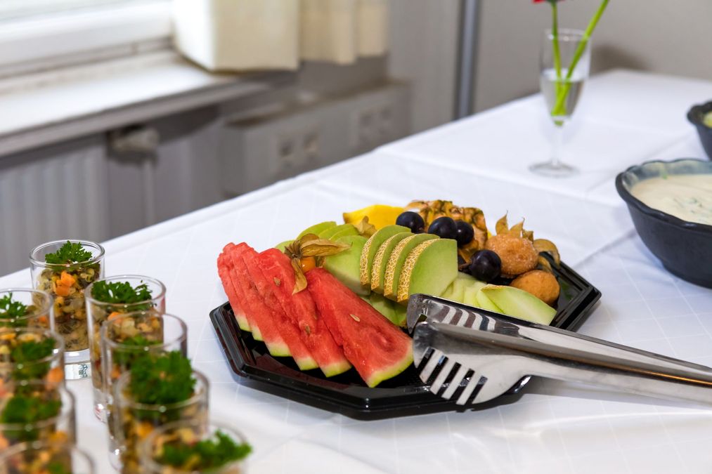 zur Vergrößerungsansicht des Bildes: Eine Cateringplatte mit frischem Obst, daneben kleine Gläser mit Salat