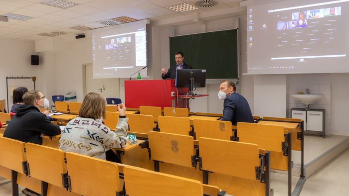 Zu sehen ist ein Seminar, das hybrid, also in Präsenz wie auch digital, gehalten wird. 