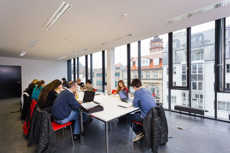 Mehrere Personen sitzen an einem großen Tisch beisammen und arbeiten an ihren Computern, Foto: Christian Hüller 