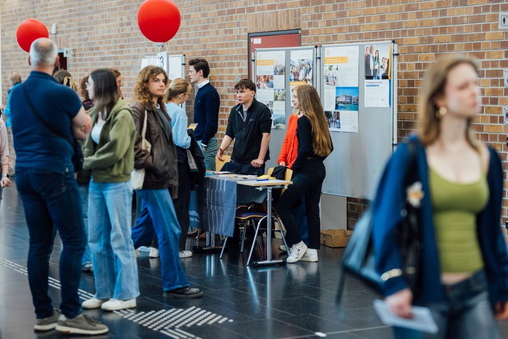 zur Vergrößerungsansicht des Bildes: Foto: Besucher:innen im Gespräch an einem Infostand.