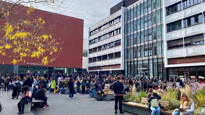 Viele Studierende tauschen sich im Leibniz-Forum zusammen aus, im Hintergrund zu sehen das Hörsaal- und Seminargebäude