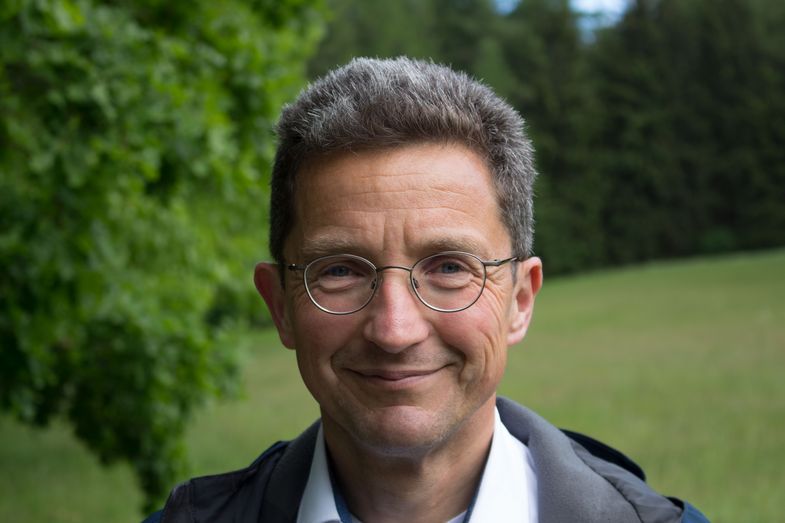 Portraitaufnahme von Prof. Dr. Alexander Deeg bei Tageslicht vor einer Bücherwand, Foto: Andreas Schüle