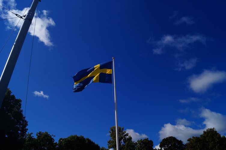 Eine schwedische Flagge weht vor blauem Himmel. 