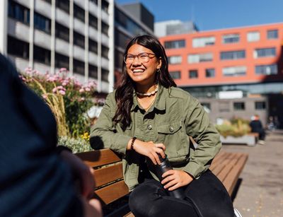 Studienbotschafterin Angela lächelt auf dem Campus, die Sonne scheint, Foto: Christian Hüller