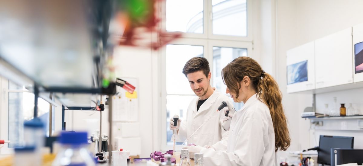 Colour photo: A man and a woman stand in the laboratory and work with scientific instruments.