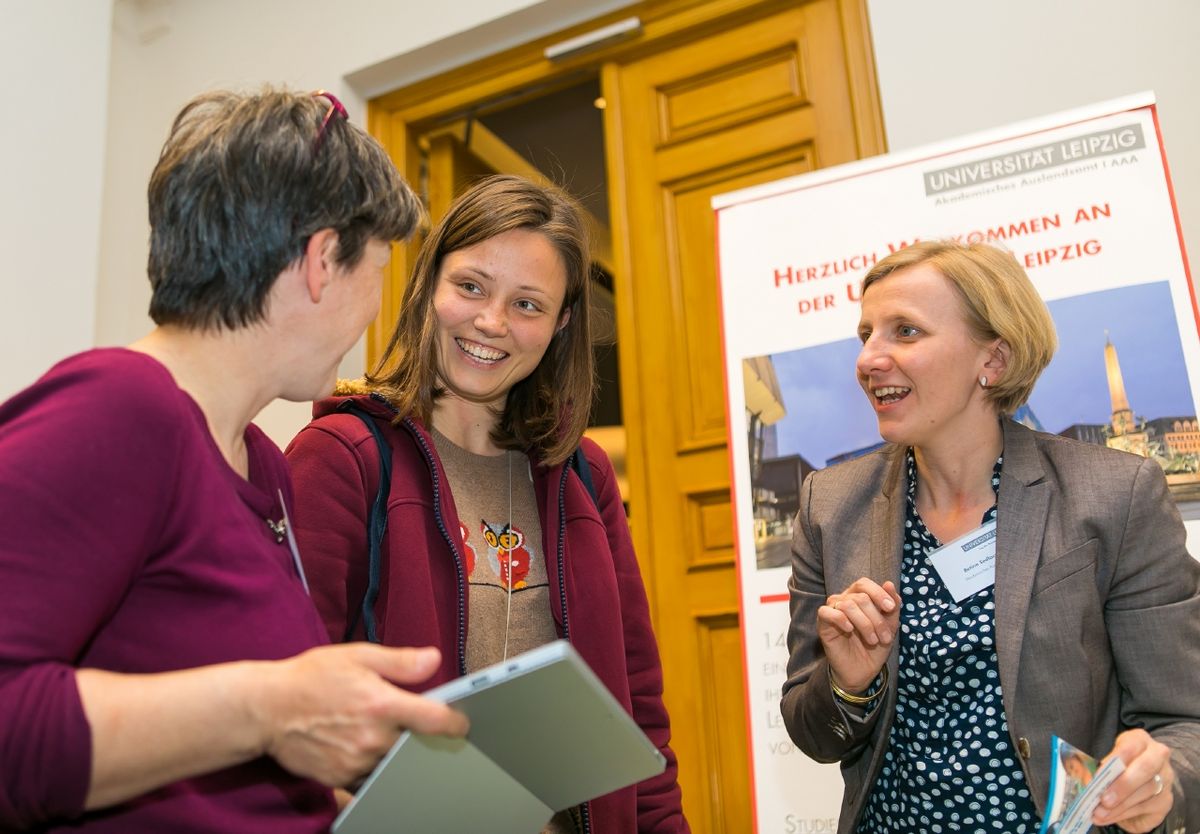 enlarge the image: Eine junge Promovierende mit zwei Frauen im Gespräch.