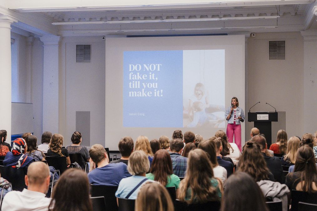 zur Vergrößerungsansicht des Bildes: Blick auf die Bühne über die Köpfe des Publikums hinweg, wo Isabell Espig ihren Vortrag startet. Im Hintergrund Ihre Präsentation. Foto: Christin Hiebner