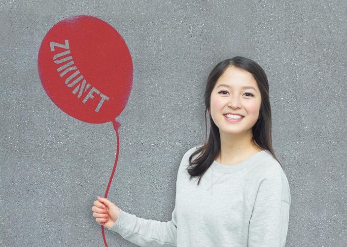 Optimistische Studentin hält Ballon mit Aufschrift "Zukunft"