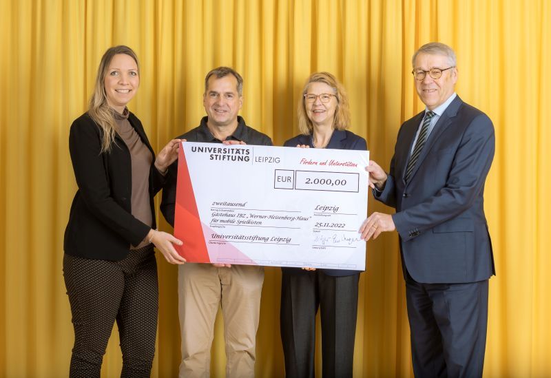 zur Vergrößerungsansicht des Bildes: Farbfoto: Prof. Dr. Birgit Dräger, Dr. Hubert Temmeyer und Prof. Dr. Harald Krautscheid von der Universitätsstiftung überreichen den symbolischen Scheck an die Fördermittelempfängerin Katharina Tosun für das IBZ Werner-Heisenberg-Haus