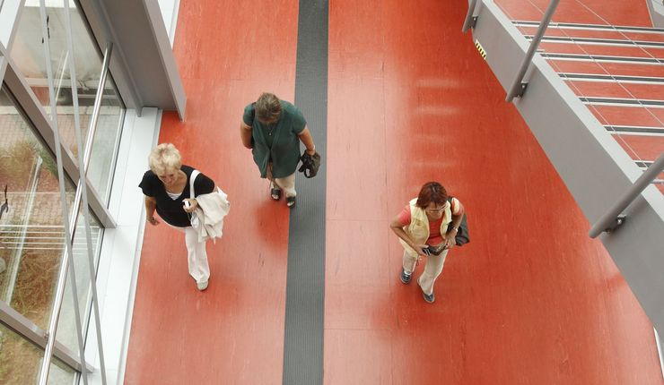 Draufsicht eines Verbindungsganges mit Treppenaufgang und laufenden Studierenden und Besucher:innen