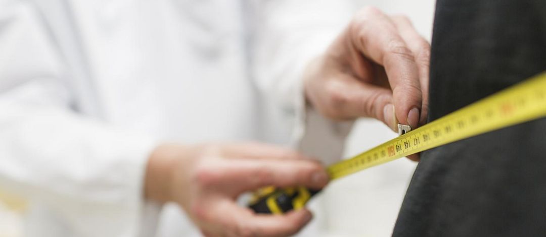 Foto: ein Arzt legt ein Maßband um den Körper eines Patienten