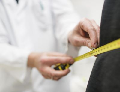 Foto: ein Arzt legt ein Maßband um den Körper eines Patienten