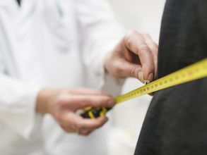 Foto: ein Arzt legt ein Maßband um den Körper eines Patienten