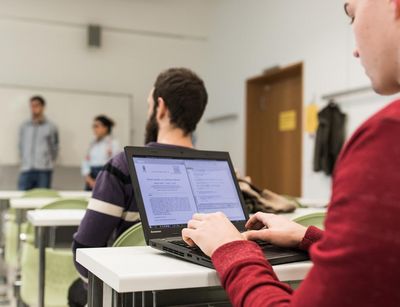 ein Student arbeitet während der Vorlesung an seinem Laptop