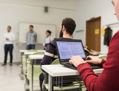 ein Student arbeitet während der Vorlesung an seinem Laptop