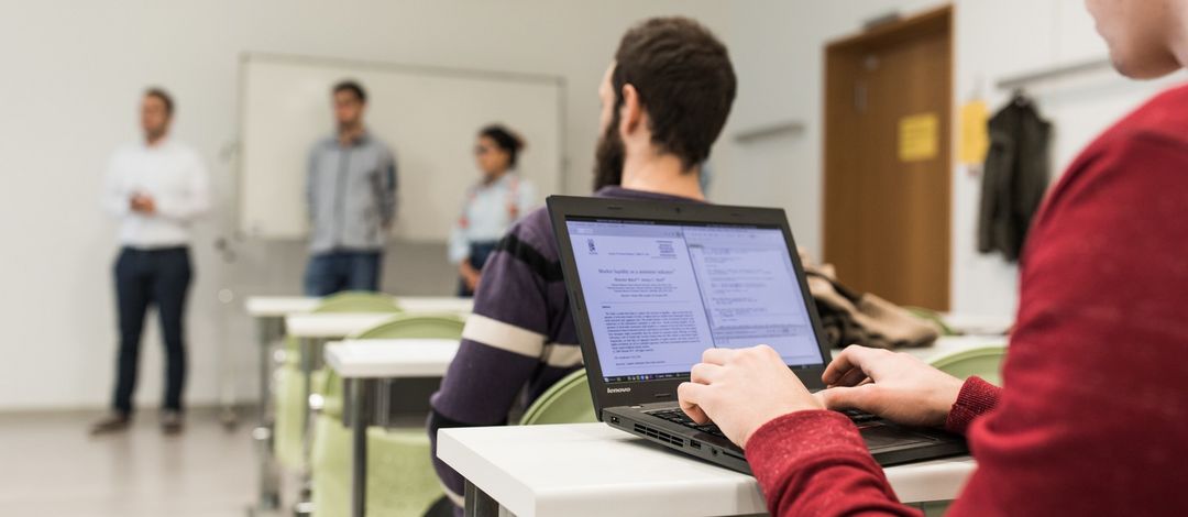 ein Student arbeitet während der Vorlesung an seinem Laptop