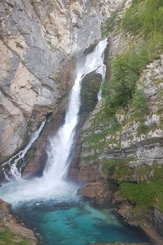 Ein Wasserfall, der aus einem Berg kommt und in einen See fällt.