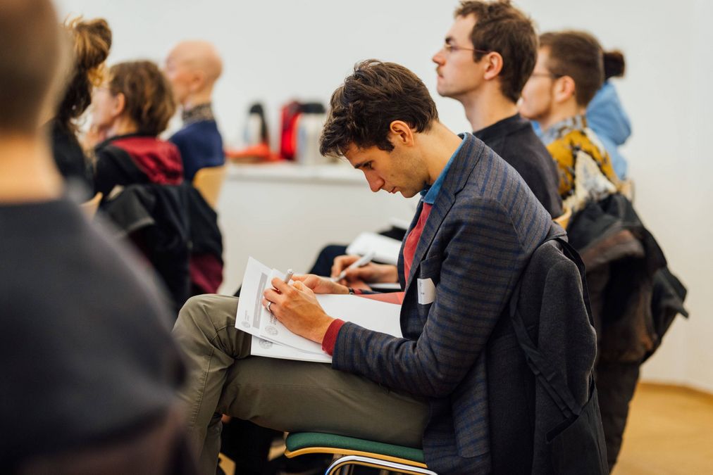 zur Vergrößerungsansicht des Bildes: Menschen sitzen in Stühlen und diskutieren einen Vortrag.