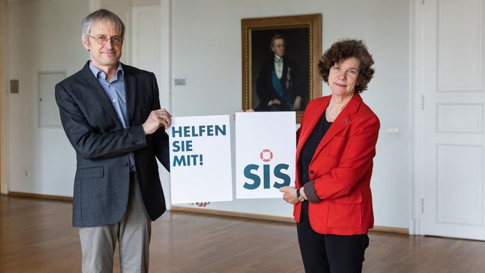 Frau Professor Schücking und Hans-Bert Rademacher halten symbolisch Schilder zur Spendenaktion.