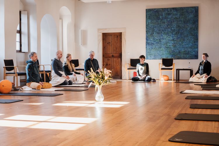 Meditierende Menschen sitzen beim Inkubationsworkshop 2022 auf Yogamatten im Kreis.