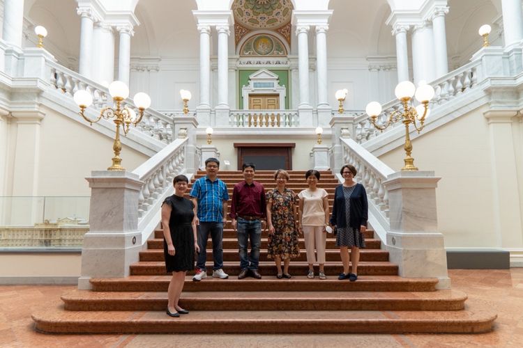 Mehrere Personen stehen in der Eingangshalle der Universitätsbibliothek auf der Treppe.