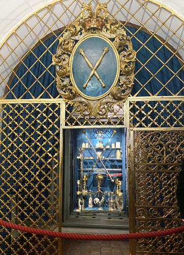 Goldene Kelche und andere Utensilien in einer Vitrine.