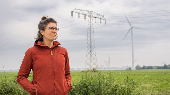 Daniela Russ vor einem Feld mit Windrad und Strommast