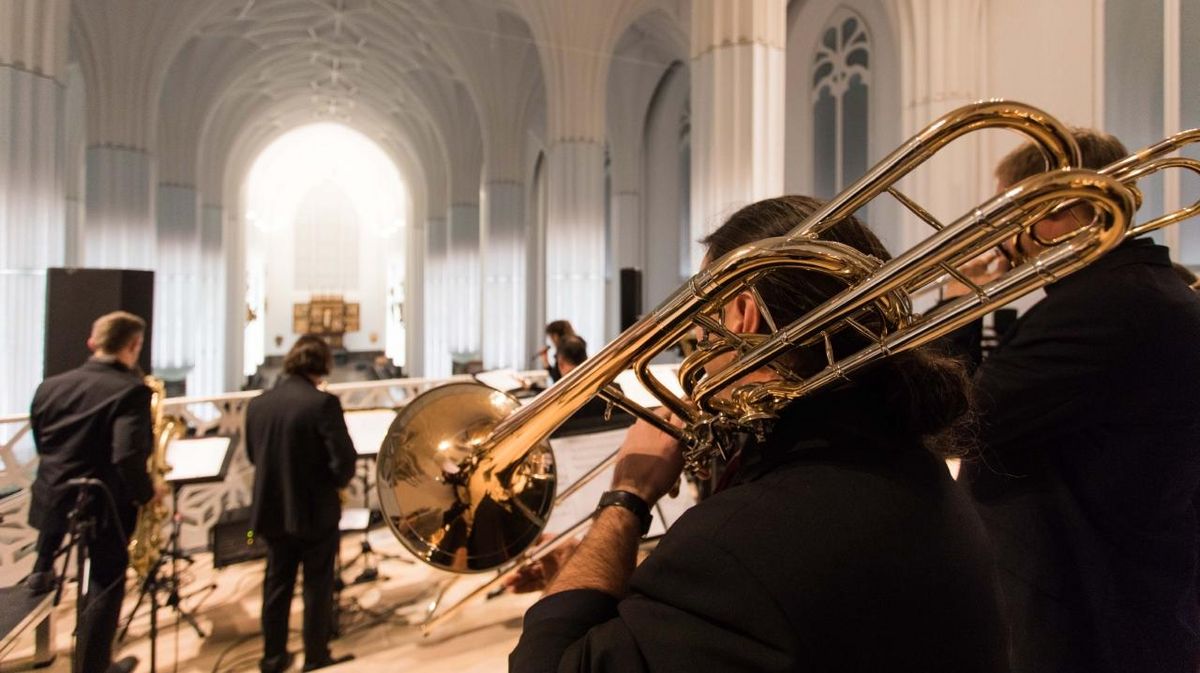 zur Vergrößerungsansicht des Bildes: Ein Trompeter steht mit dem Rücken zur Kamera. Sein Instrument steht im Fokus des Bildes.