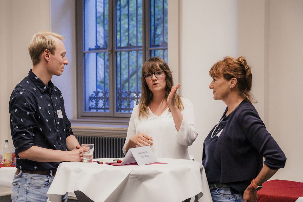 zur Vergrößerungsansicht des Bildes: Drei Teilnehmende im Austausch am Thementisch "Handel, Finanzen, Versicherung". Foto: Christin Hiebner