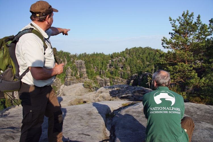 A nature conservation ranger of the Saxon Switzerland National Park, Germany, shows his colleague a forest area where he had discovered an illegal fireplace. Picture: Hanspeter Mayr, Saxon Switzerland National Park