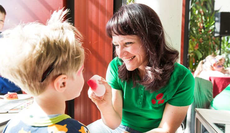 Foto: eine Frau die Kinder schminkt