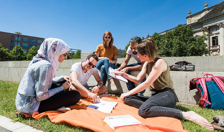 Grupper internationaler Studierender sitzt auf dem Campus Augustusplatz