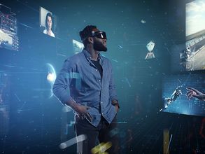 Computergrafik: Mensch mit einer Brille für virtuelle Realität umgeben von Bildschirmen, auf denen Roboter, eine Straße und Mensch-Maschine-Verbindungen zu sehen sind.